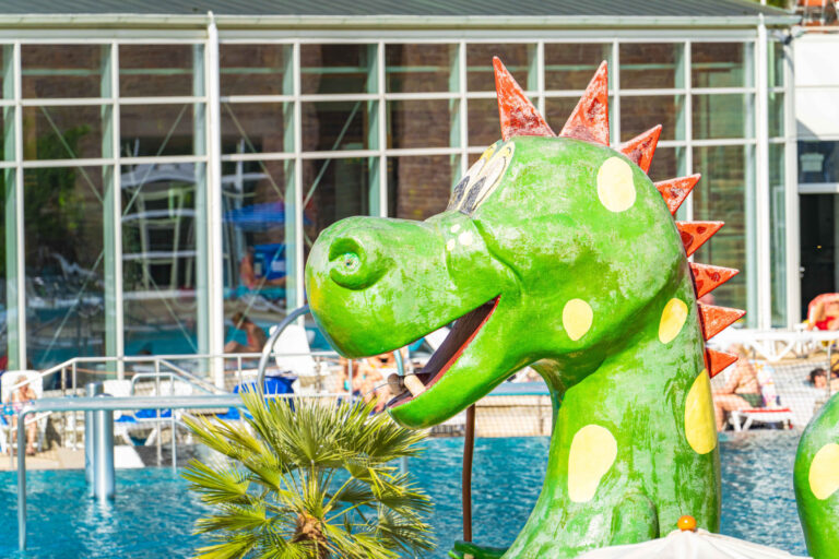 Detailaufnahme des grünen Drachens mit roten Zacken im Kinderbereich des Freibads.
