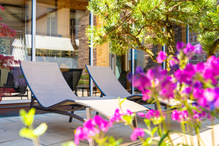 Zwei Liegestühle auf der sonnigen Terrasse der Saunawelt.